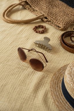 Sarı muslin kumaşlı kadın plaj aksesuarları. Kemer, hasır çanta, güneş gözlüğü, şapka, güneş gözlüğü. Seyahat blogu ve sosyal medya için estetik lüks boho kavramı