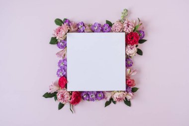 Pembe arka planda gül tomurcuklarından yapılmış çerçeve ve boş kağıt kağıtlar. Düz yerde, üst tarafta. Boşluk modellemesini kopyala.