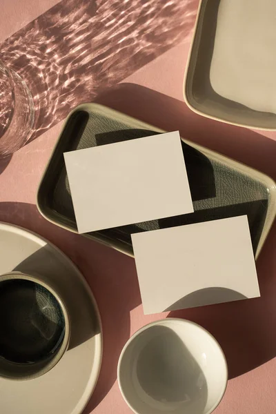 空白纸卡片 在灰粉色背景上有模拟复制空间 美感波希米亚商业品牌模板 带有闪亮阳光阴影的陶瓷盘和玻璃杯 — 图库照片