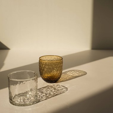 Minimum lüks modern iç tasarım konsepti. Tarafsız bej arka planda parlak güneş ışığı gölgesi olan bohem kristal cam.