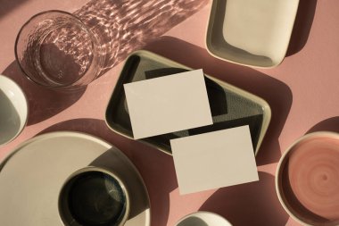 Fotokopi alanı olan boş kağıt kağıdı. Minimum lüks, estetik, marka şablonu. Güneş ışığı gölgeli cam, tozlu pembe arka planda seramik plakalar. Düz yatış, üst görünüm