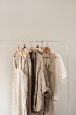 Yıkanmış çarşaflardan yapılmış kadınların en az moda pastel kıyafetleri. Şık kadın bluzları, elbiseler, pantolonlar, beyaz arka planda askıda asılı gömlekler. Moda blogu, web sitesi, sosyal medya