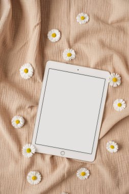 Blank screen tablet pad with mockup copy space and dry floral branch and neutral beige muslin cloth. Minimal aesthetic business workspace template. Flat lay, top view clipart