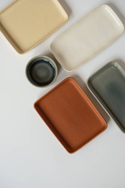Tarafsız renk seramik, boş el yapımı seramik tabaklar ve beyaz arka planda kaseler. Düz yatış, üst görünüm
