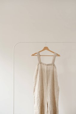 Minimalist gardırop: nötr bej renginde çamaşır giysisi ya da beyaz duvara asılı elbise. Estetik moda konsepti