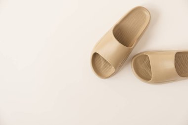 Tarafsız bej renkli yaz terlikleri beyaz arka planda izole edilmiş. Düz yatış, üst görünüm minimalist moda kavramı