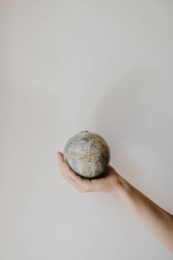 Beyaz arka planda küçük bir dünya tutan bir kadın. Dünya, Dünya modeli ellerinde. Dünya ve çevre kavramını kaydet