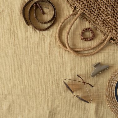 Sarı muslin kumaşlı kadın plaj aksesuarları. Kemer, hasır çanta, güneş gözlüğü, şapka, güneş gözlüğü. Seyahat blogu için estetik lüks boho konsepti, sosyal medya. Düz yatış, üst görünüm
