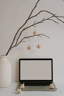 Dizüstü bilgisayarı, dekoratif vazosu ve kağıt fenerleri olan modern minimalist masa. Temiz, basit, estetik ve doğal aksanlı nötr çalışma alanı