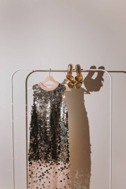 Sequin Elbise ve Altın Topuklar, Gölgeler Oyunuyla Minimalist Rack 'te. Şık Akşam Giyimi, Moda Stili, Göz kamaştırıcı Kıyafet İlhamı, Minimalist Moda Estetiği, Şık Kıyafet Gösterimi