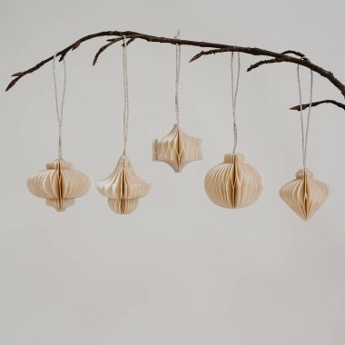 Minimalist dekor. Tarafsız Arkaplan Karşısında Çıplak Dallarda Asılı Zarif Kağıt Süslemeler. Sanatsal Basitlik, İskandinav Tarzı, Çevre dostu Tasarım, İç Estetik