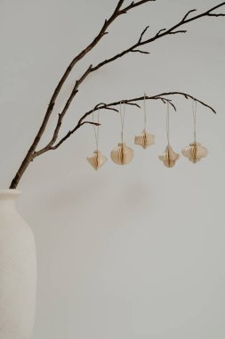 Seramik vazo dallı minimalist dekoru ve asılı kağıt süslemeleri. Doğal Estetik, Tarafsız Tonlar, Basit Tasarım, İskandinav Tarzı, İç Dekorasyon