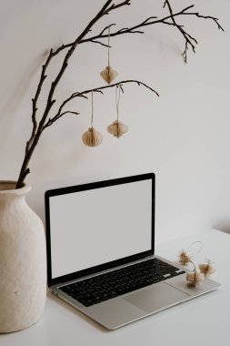 Dizüstü bilgisayarı, nötr vazosu ve asılı kağıt fenerleri olan en az çalışma alanı. Doğal elementlerle donatılmış rahat, nötr masa. Basit ofis dekorasyonu ve temiz modern estetik.