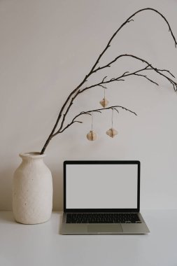 Laptop, toprak vazo ve kağıt fener süslemeleri ile şık bir ofis düzeni. Sakin nötr tonlara sahip estetik çalışma ortamı, asgari dekor