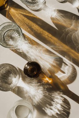 Güneş Işığı Kristal Gözlükleri ve Kehribar Şişe, Minimalist Ayarlarda Altın Yansımalar