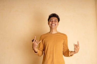 Neşeli genç bir adam bir kaya işaretiyle mutluluğu ifade ediyor..