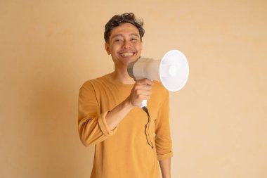 Elinde megafonla, sıcak bir stüdyoda neşe saçan neşeli bir genç..