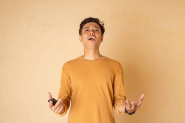 Genç bir adam açık elle şaşkınlık ve hassasiyet gösterir..