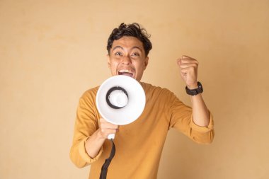 Enerjik bir heyecan gösterisinde megafonu tutkuyla kullanan neşeli genç bir adam..