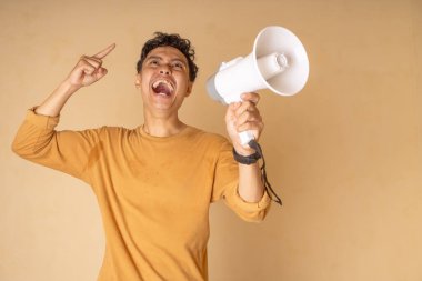 Heyecan ve enerjiyi ifade etmek için megafonu tutkuyla kullanan neşeli bir genç..