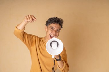 Neşeli genç bir adam enerjik bir şekilde megafona bağırıyor, canlı bir kutlama sergiliyor..