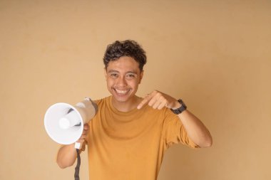 Neşeli genç bir adam megafonu işaret ediyor, heyecan ve enerji gösteriyor..
