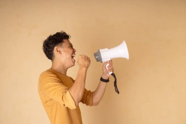 Genç bir adam tutkulu bir şekilde megafona bağırıyor, canlı enerji ve coşkuyu vurguluyor..