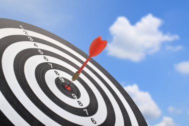 Dart tahtasının ortasındaki kırmızı ok mavi gökyüzü arka planına karşı. Doğruluğu, başarıyı, hedef başarısını ve odaklanmayı simgeler..