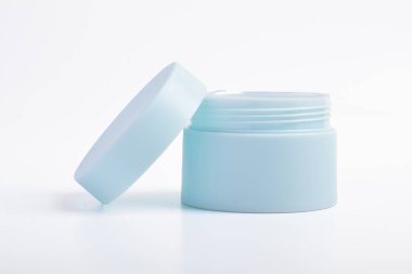 Beyaz arka planı açık kapaklı mavi kozmetik kavanoz kabı.