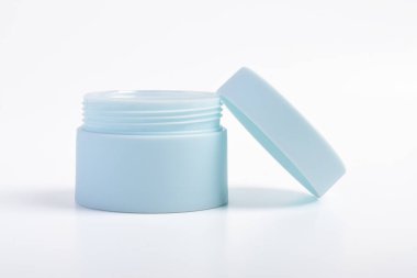 Beyaz arka planı açık kapaklı mavi kozmetik kavanoz kabı.