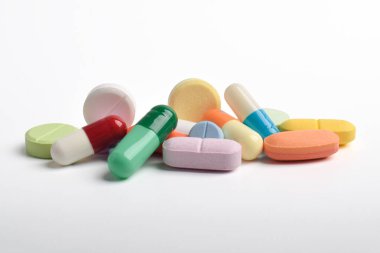 Beyaz arka planda çeşitli renkli haplar ve kapsüller, çeşitli ilaçlar, vitaminler ve sağlık hizmetleri ve eczane konseptine ilaveler.