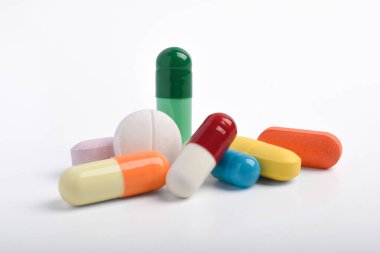 Beyaz arka planda çeşitli renkli haplar ve kapsüller, çeşitli ilaçlar, vitaminler ve sağlık hizmetleri ve eczane konseptine ilaveler.