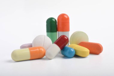 Beyaz arka planda çeşitli renkli haplar ve kapsüller, çeşitli ilaçlar, vitaminler ve sağlık hizmetleri ve eczane konseptine ilaveler.