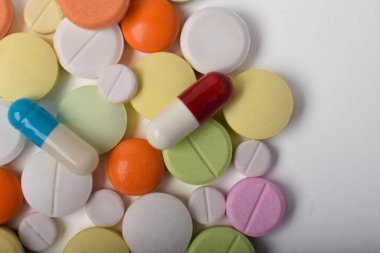 Beyaz arka planda çeşitli renkli haplar ve kapsüller, çeşitli ilaçlar, vitaminler ve sağlık hizmetleri ve eczane konseptine ilaveler.