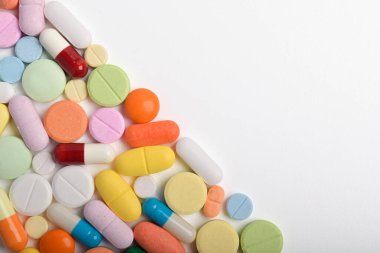 Çeşitli renkli haplar ve kapsüller bir çerçeve oluşturur, beyaz bir arkaplanda izole edilmiş, metin için uzayı kopyalayarak. Tıbbi konsept.
