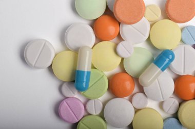 Beyaz arka planda çeşitli renkli haplar ve kapsüller, çeşitli ilaçlar, vitaminler ve sağlık hizmetleri ve eczane konseptine ilaveler.