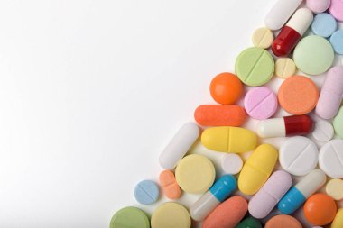 Çeşitli renkli haplar ve kapsüller bir çerçeve oluşturur, beyaz bir arkaplanda izole edilmiş, metin için uzayı kopyalayarak. Tıbbi konsept.