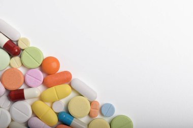 Çeşitli renkli haplar ve kapsüller bir çerçeve oluşturur, beyaz bir arkaplanda izole edilmiş, metin için uzayı kopyalayarak. Tıbbi konsept.