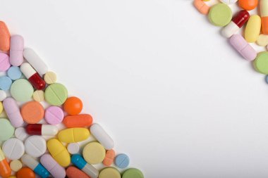 Çeşitli renkli haplar ve kapsüller bir çerçeve oluşturur, beyaz bir arkaplanda izole edilmiş, metin için uzayı kopyalayarak. Tıbbi konsept.