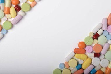 Çeşitli renkli haplar ve kapsüller bir çerçeve oluşturur, beyaz bir arkaplanda izole edilmiş, metin için uzayı kopyalayarak. Tıbbi konsept.