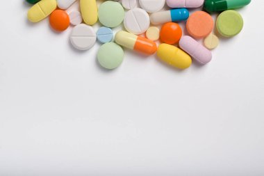 Çeşitli renkli haplar ve kapsüller bir çerçeve oluşturur, beyaz bir arkaplanda izole edilmiş, metin için uzayı kopyalayarak. Tıbbi konsept.