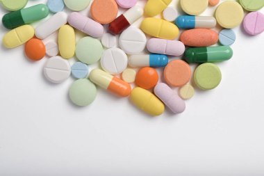 Çeşitli renkli haplar ve kapsüller bir çerçeve oluşturur, beyaz bir arkaplanda izole edilmiş, metin için uzayı kopyalayarak. Tıbbi konsept.