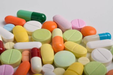 Beyaz arka planda çeşitli renkli haplar ve kapsüller, çeşitli ilaçlar, vitaminler ve sağlık hizmetleri ve eczane konseptine ilaveler.