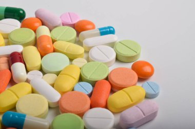 Beyaz arka planda çeşitli renkli haplar ve kapsüller, çeşitli ilaçlar, vitaminler ve sağlık hizmetleri ve eczane konseptine ilaveler.