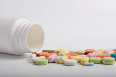 Beyaz arka planda çeşitli renkli haplar ve kapsüller, çeşitli ilaçlar, vitaminler ve sağlık ve eczane konseptindeki takviyeler.