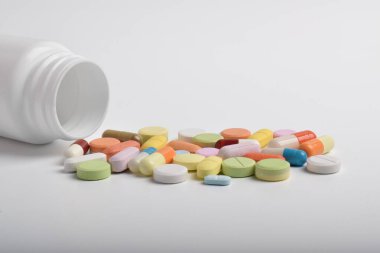 Beyaz arka planda çeşitli renkli haplar ve kapsüller, çeşitli ilaçlar, vitaminler ve sağlık ve eczane konseptindeki takviyeler.