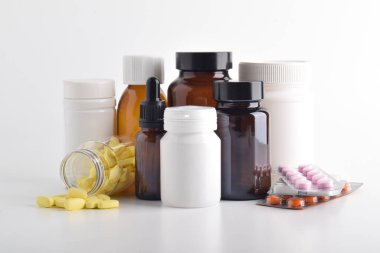 Beyaz arka planda çeşitli haplar ve ilaç şişeleri var. Sağlık ürünleri ve tıbbi tedavi malzemeleri kavramı.