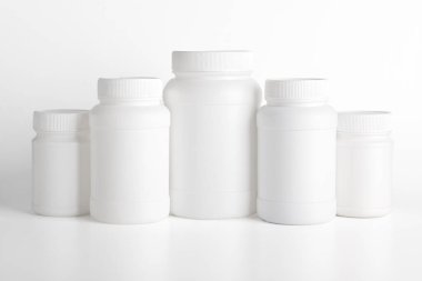 Beyaz arka planda çeşitli boyutlarda boş beyaz plastik ilaç şişeleri, ilaç ambalajı ve ürün modellemesi.