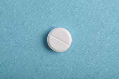 Mavi arka planda izole edilmiş beyaz bir hap. Üst manzara, düz uzanma.