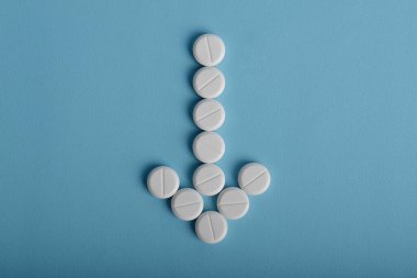 Mavi arka planda izole edilmiş ok şeklinde tıbbi haplar..